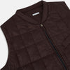 View 2 of product The Turnbull & Asser Burgundy Quilted Gilet is a sleeveless, lightweight layer featuring a front zipper, slanted chest pocket, adjustable side tabs, and two zippered side pockets, shown on a plain white background.
