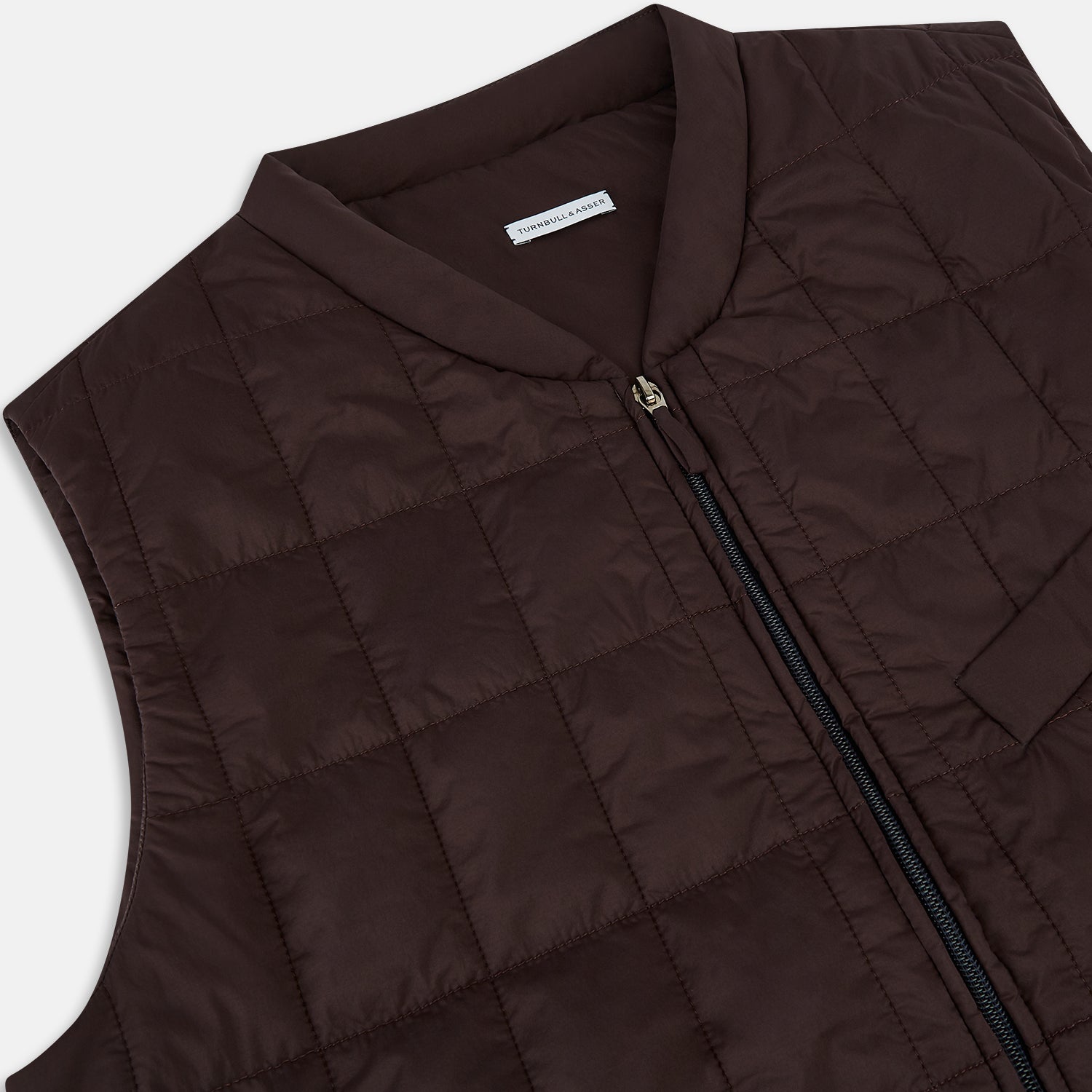 View 2 of product The Turnbull & Asser Burgundy Quilted Gilet is a sleeveless, lightweight layer featuring a front zipper, slanted chest pocket, adjustable side tabs, and two zippered side pockets, shown on a plain white background.
