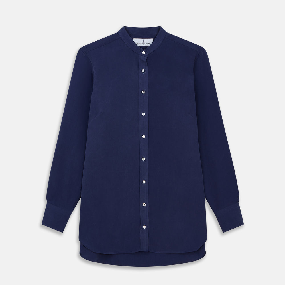 The Turnbull & Asser Blue Soft-touch Silk Lauren Shirt is a navy, long-sleeve button-up with an Igret stand collar, white buttons, curved hem, relaxed fit, and elongated body for a modern look, shown laid flat on a white background.