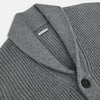 View 2 of product The Turnbull & Asser Grey Melange Cashmere Shawl Collar Cardigan features a ribbed-knit texture, five black front buttons, and two pockets, shown against a plain white background.