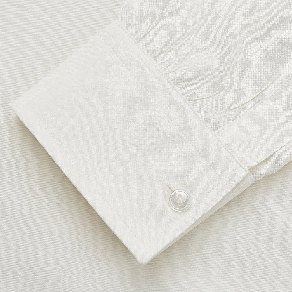The Cream Silk Long Point Embroidered Eamon Shirt by Turnbull & Asser features long sleeves, a pointed collar, and delicate botanical embroidery. Its buttoned cuffs and tailored fit make it an elegant partywear choice.