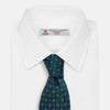 View 2 of product The MINI SQUARE SPOT FOREST GREEN BLUE TIE by Turnbull & Asser is a classic men's accessory, featuring a rolled-up green silk design with small blue geometric patterns—perfect for the modern gentleman.