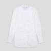 View 2 of product A person with curly hair wears the Turnbull and The Deck White Cotton Minimalist Shirt by Turnbull & Asser, paired with pants. Posed against a plain background, their minimalist silhouette is highlighted in this black and white image.