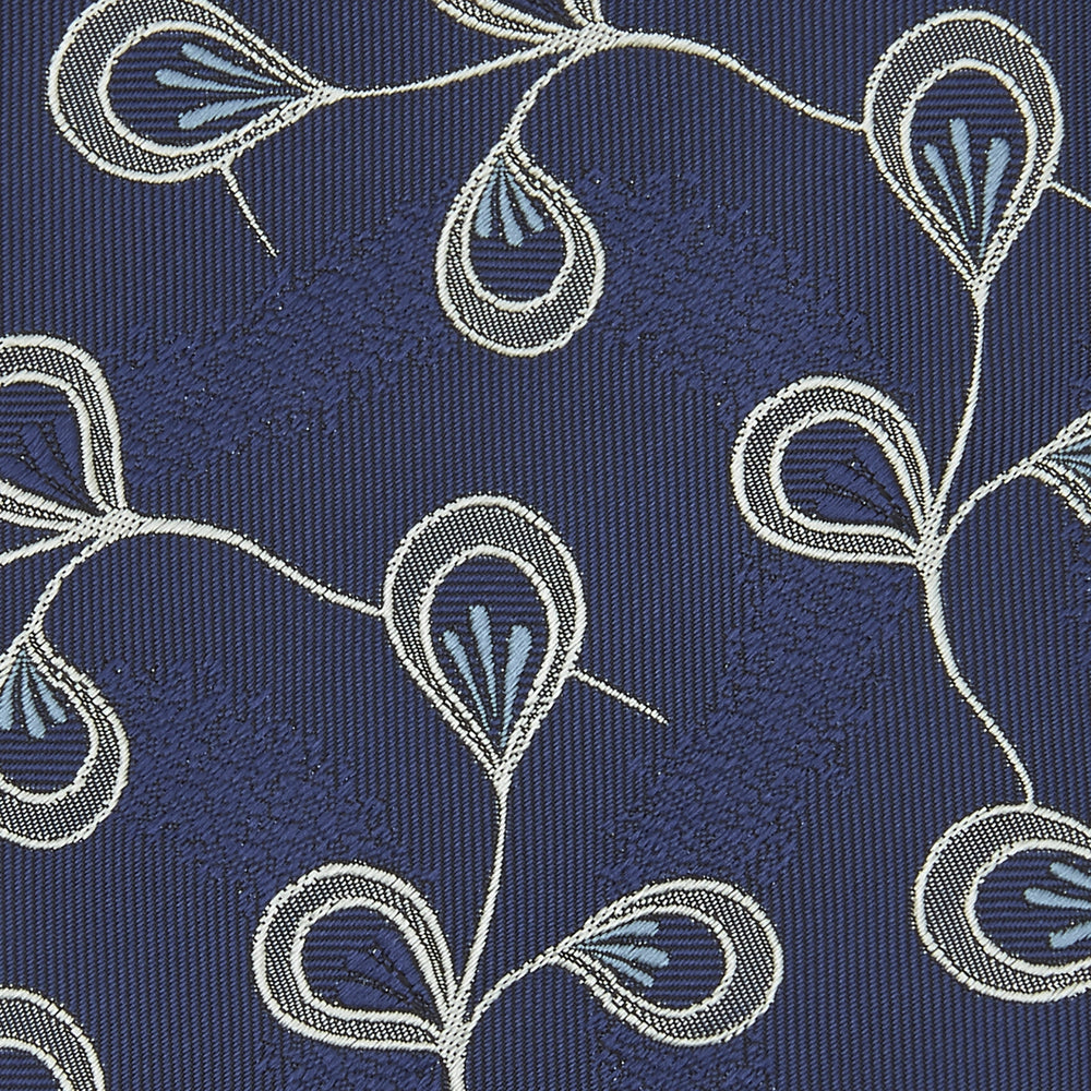 The Turnbull & Asser Navy Jacquard Silk Floral Tie features white and light blue abstract leaf designs, exemplifying fine British craftsmanship. Shown rolled up against a white background.