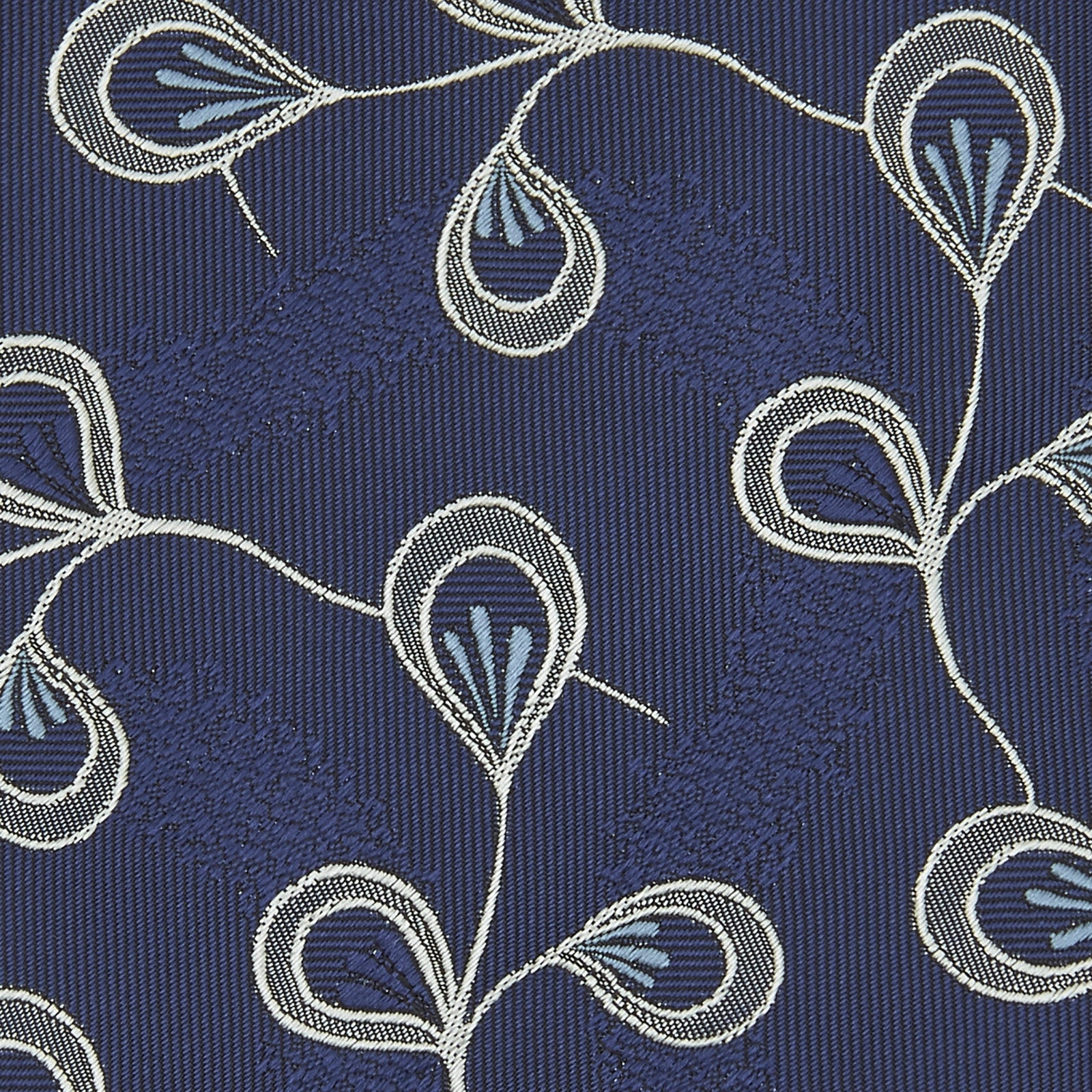 View 4 of product The Turnbull & Asser Navy Jacquard Silk Floral Tie features white and light blue abstract leaf designs, exemplifying fine British craftsmanship. Shown rolled up against a white background.