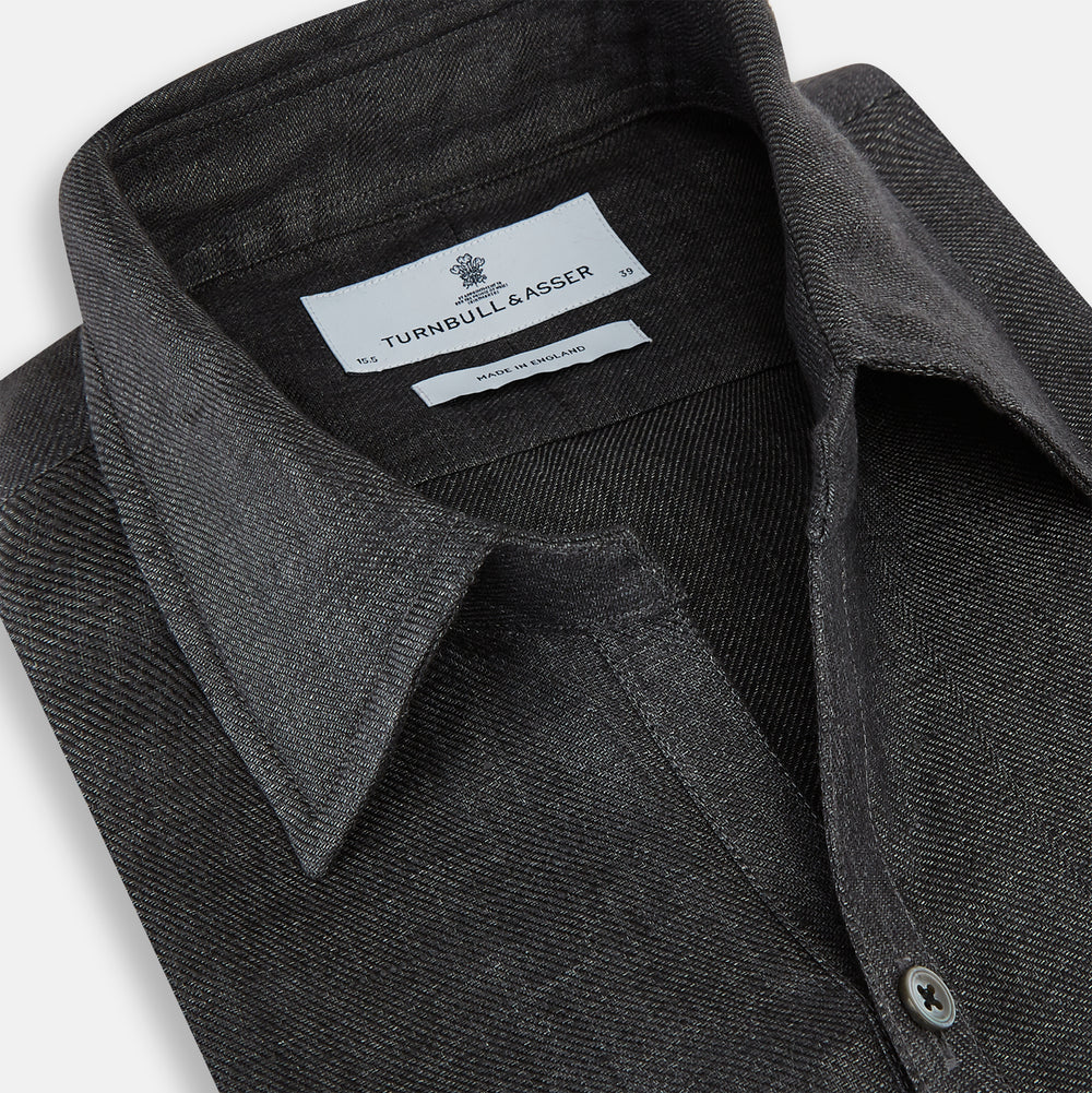 The Ash Linen Windsor Shirt by Turnbull & Asser is a long-sleeve, button-up black shirt with a Windsor collar and cuffs, reflecting British craftsmanship, shown on a plain white background.