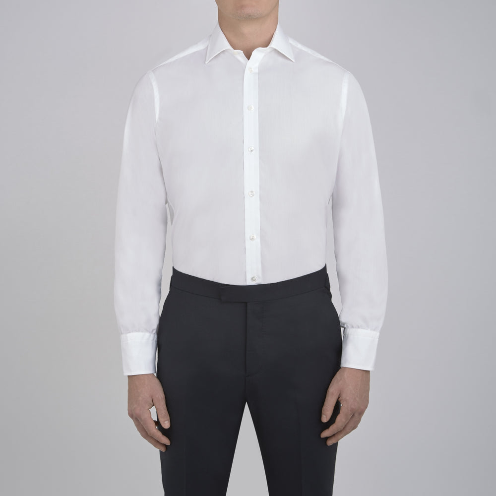 The Sea Island Cotton Classic Fit White Shirt by Turnbull & Asser features a classic collar and front buttons, neatly folded with its label visible, displayed on a light blue background.