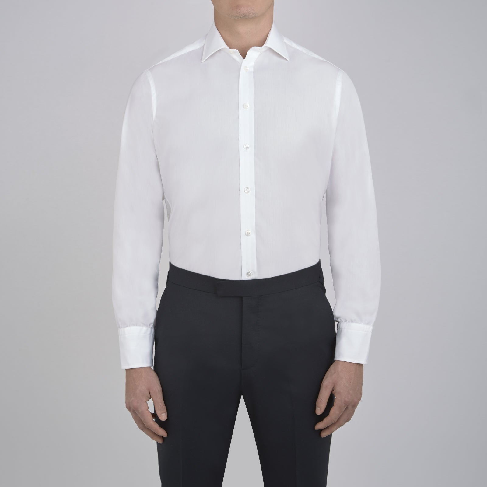 View 2 of product The Sea Island Cotton Classic Fit White Shirt by Turnbull & Asser features a classic collar and front buttons, neatly folded with its label visible, displayed on a light blue background.