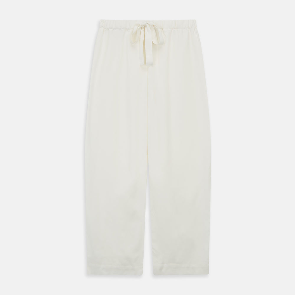 The Women's Harriet Cream Silk Pyjama Set by Turnbull & Asser features a white sand-washed silk button-up top with black piping and chest pocket, plus matching drawstring pants, all shown against a white background.