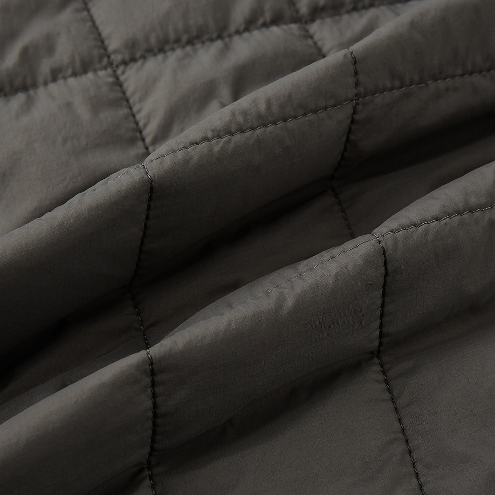 The Battersea Shadow Grey Quilted Jacket by Turnbull & Asser features a front zipper, buttoned cuffs, pointed collar, and multiple pockets—an ideal choice for the modern gentleman. Shown on a plain white background.