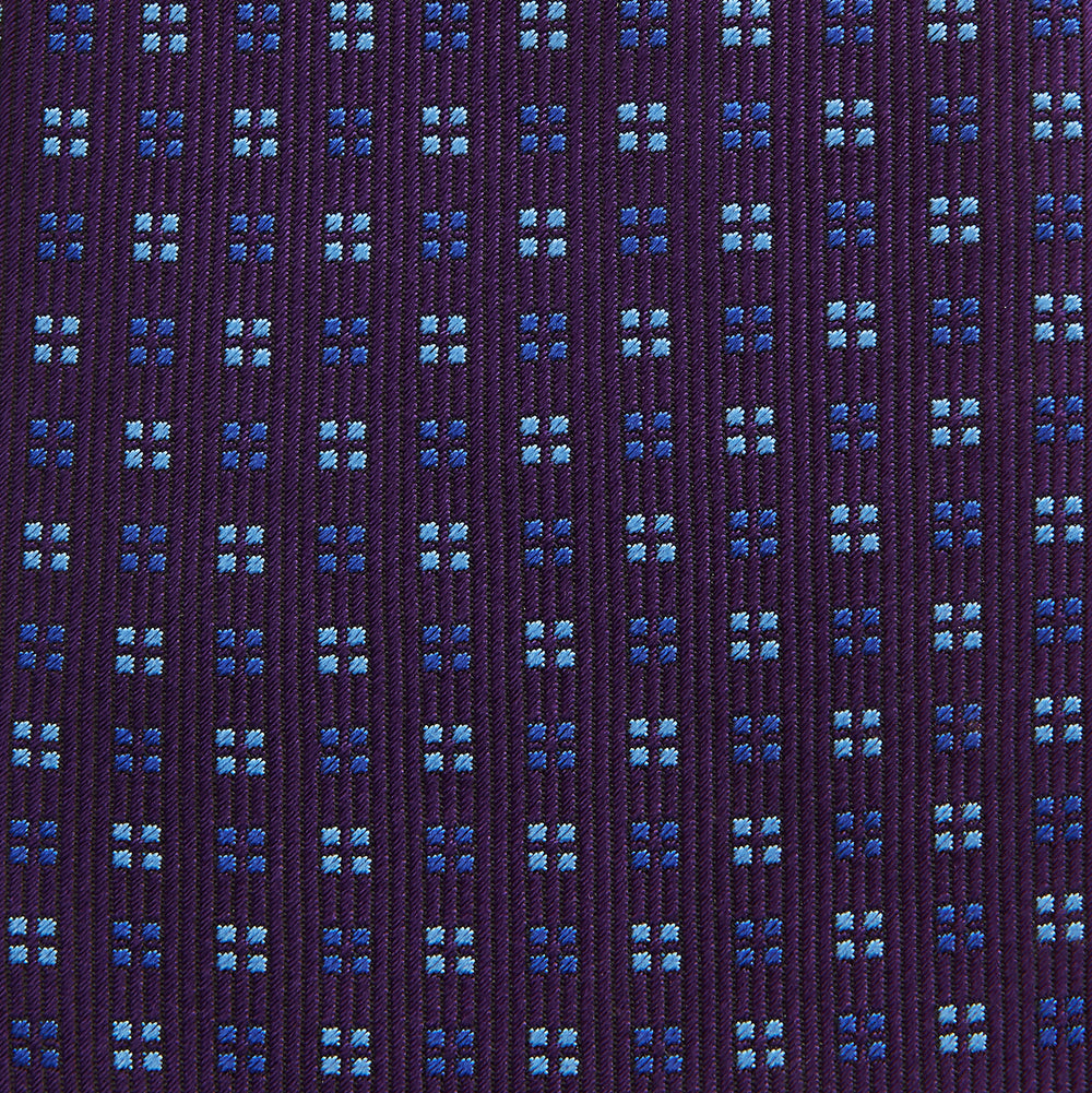 The Turnbull & Asser MINI SQUARE SPOT PLUM BLUE TIE is a luxury English silk necktie in plum, featuring a blue and white grid pattern of small squares, displayed rolled up against a simple light background.