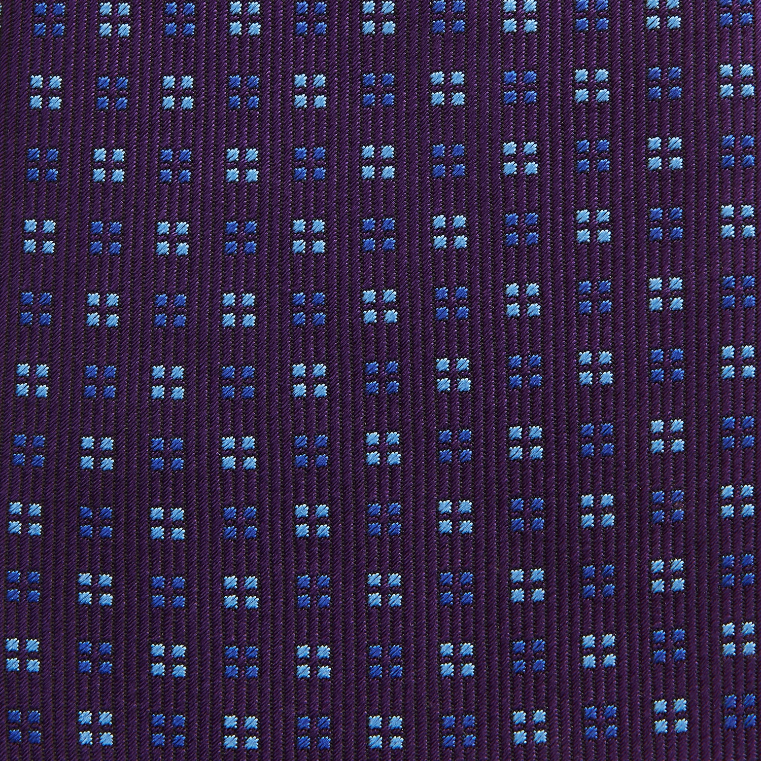 View 3 of product The Turnbull & Asser MINI SQUARE SPOT PLUM BLUE TIE is a luxury English silk necktie in plum, featuring a blue and white grid pattern of small squares, displayed rolled up against a simple light background.