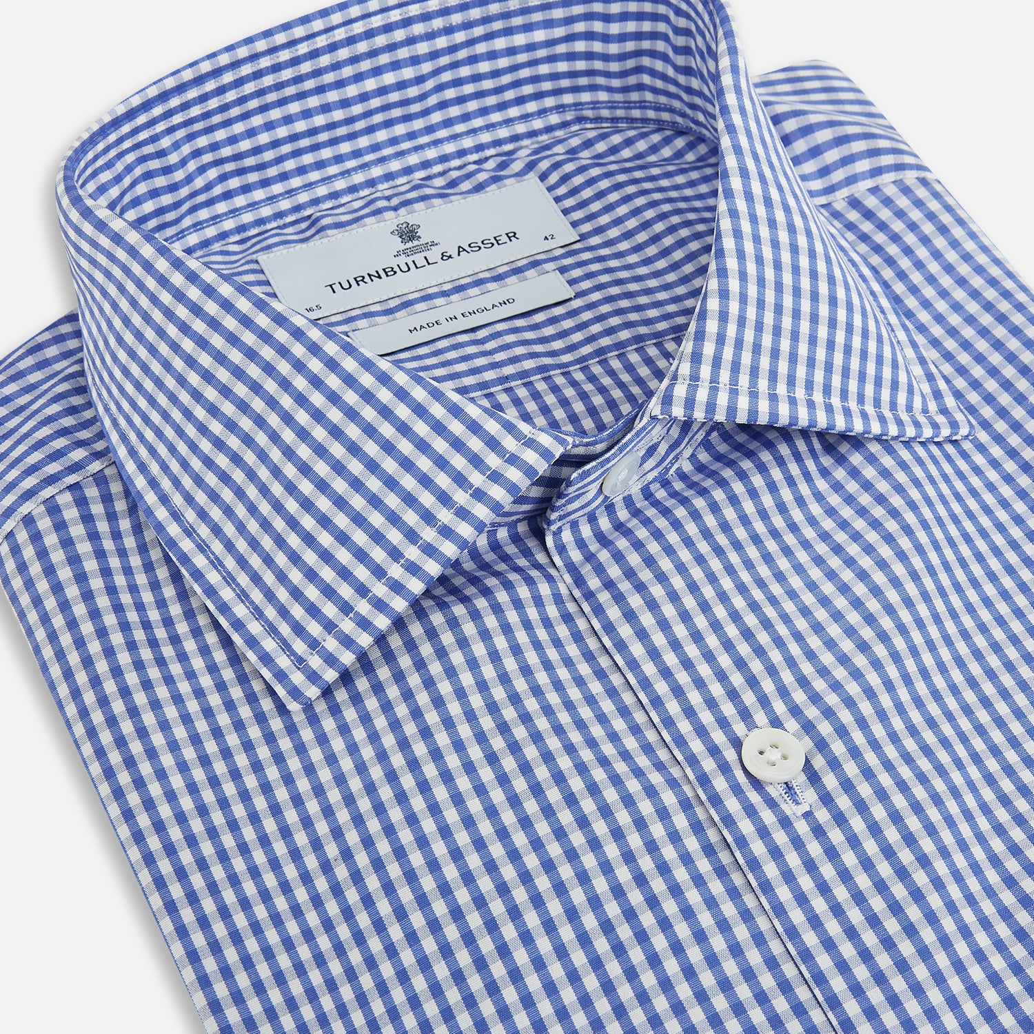 View 2 of product The Turnbull & Asser Blue Grid Check Belgravia Shirt, made from pure cotton with long sleeves, a spread collar, buttoned cuffs, and a blue-and-white check pattern, is laid flat on a white background.