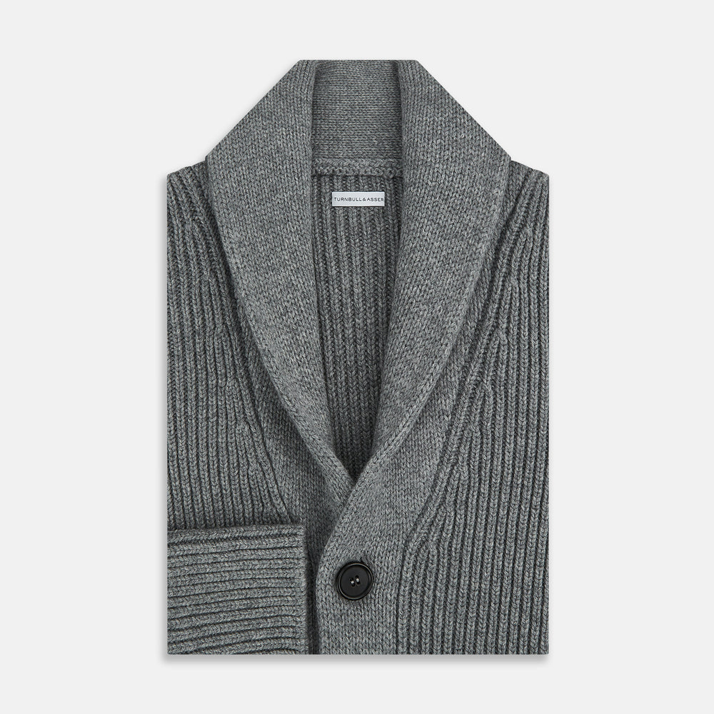 The Turnbull & Asser Grey Melange Cashmere Shawl Collar Cardigan features a ribbed-knit texture, five black front buttons, and two pockets, shown against a plain white background.