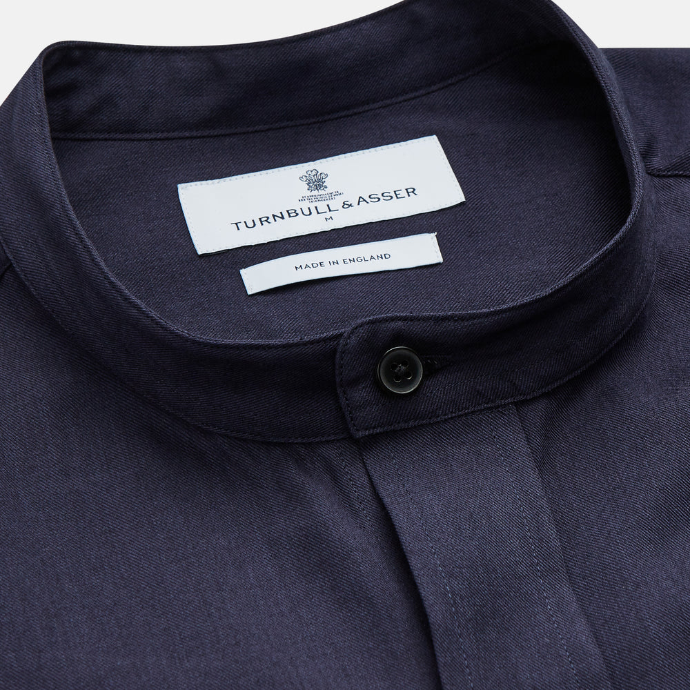 The Turnbull & Asser Navy Military Weekend Fit Shirt features a stand collar, black buttons, dual chest flap pockets, and 1-button cuffs in Italian cotton-wool, shown laid flat on a white background.