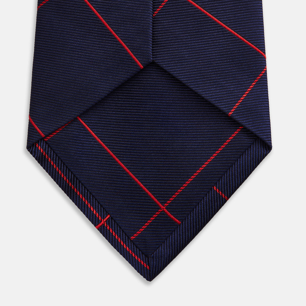 The Turnbull & Asser Red and Navy Window Pane Silk Tie features a refined diagonal red pattern on navy silk, making it an elegant choice for office attire.
