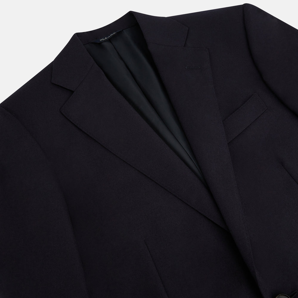The Turnbull & Asser Long Navy Single Breasted Suit, shown on a white background, features a blazer with notch lapels and matching tailored trousers—ideal for formal occasions.