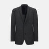 View 1 of product The Turnbull & Asser Graphite Knitted Oxford Blazer for men features a dark gray hue, two buttons, notched lapels, and three front pockets—a modern British-inspired piece styled elegantly against a light background.