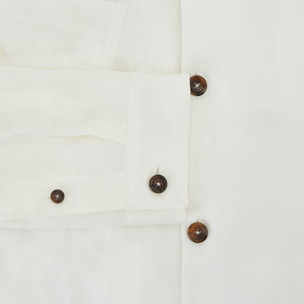 The Vanilla Linen Holland Shacket by Turnbull & Asser, a white Irish linen button-up with a collar, brown buttons, and four pockets, is laid flat on a white background—perfect as lightweight outerwear.