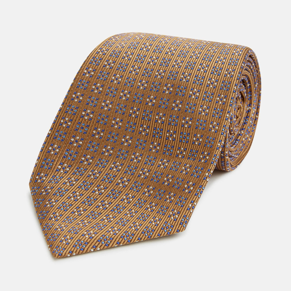 The Turnbull & Asser Tan and Blue Multi Dot Silk Tie is rolled up, showcasing a refined dotted pattern on silk—an elegant accessory ideal for elevating modern office attire.