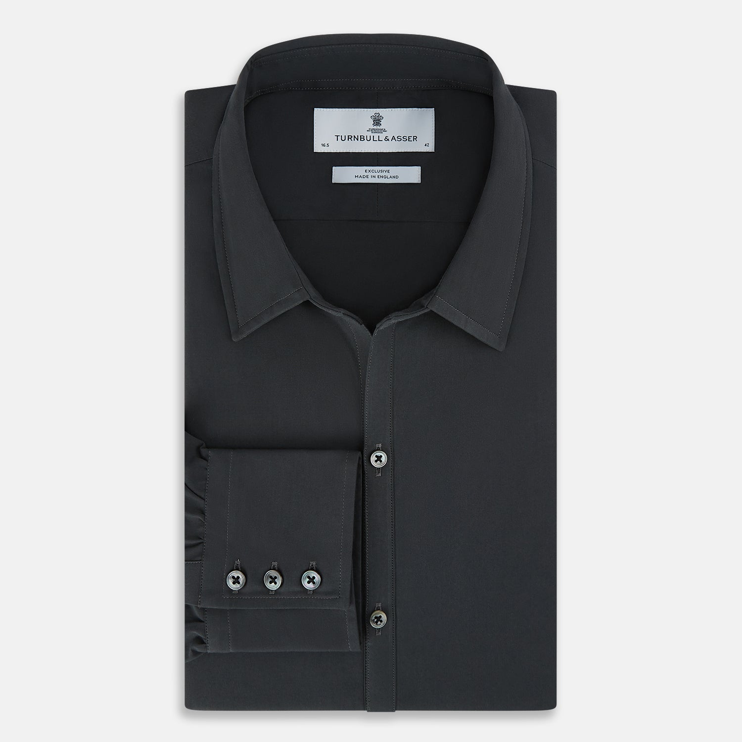 View 5 of product The Charcoal Windsor Shirt by Turnbull & Asser is a black, long-sleeve button-up with a pointed Windsor collar, buttoned cuffs, and a straight hem, shown flat on a white background.