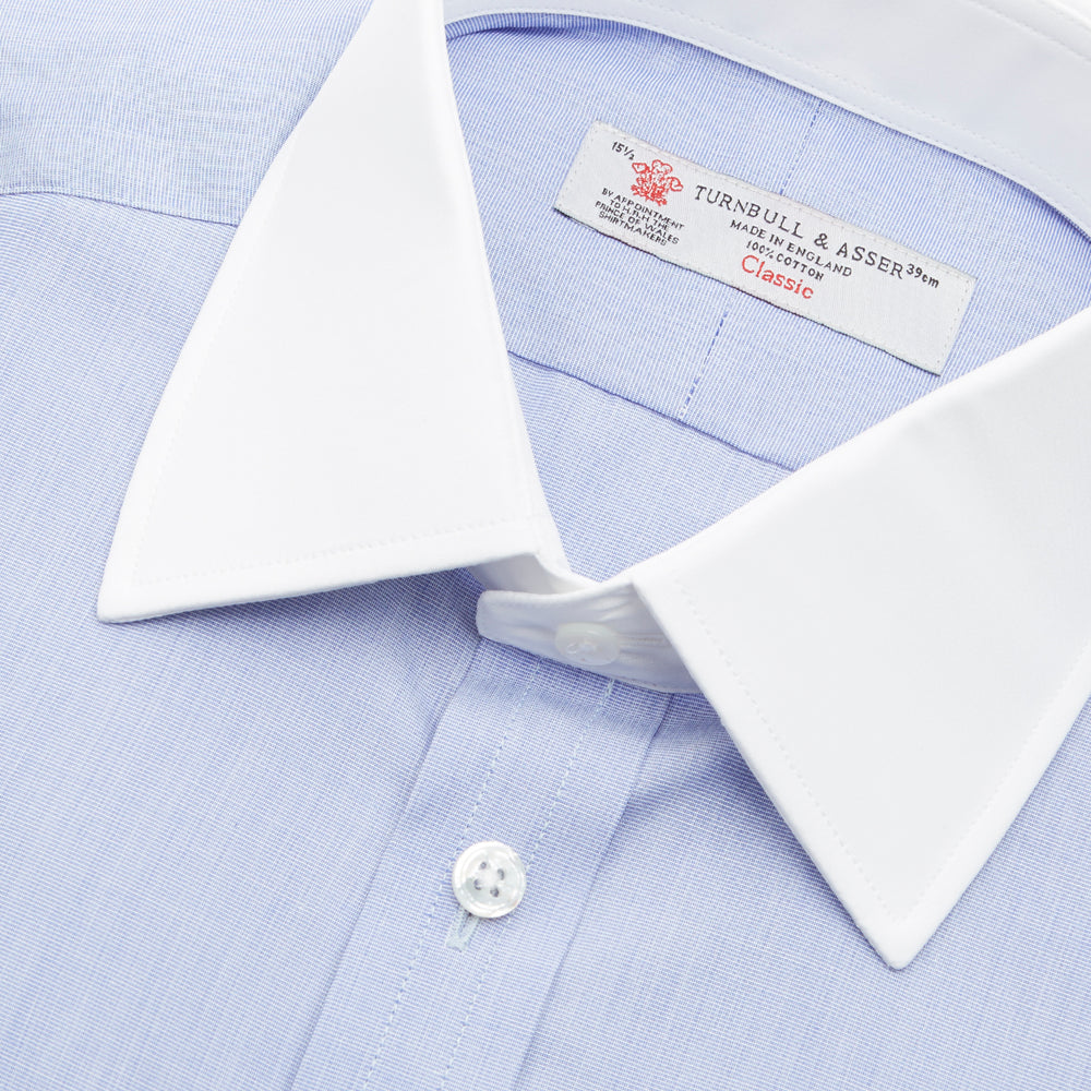The Wall Street Shirt with White T&A Collar by Turnbull & Asser, as seen on Gordon Gekko, is folded neatly to showcase its light purple color, crisp French cuffs, and iconic contrasting collar against a plain background.
