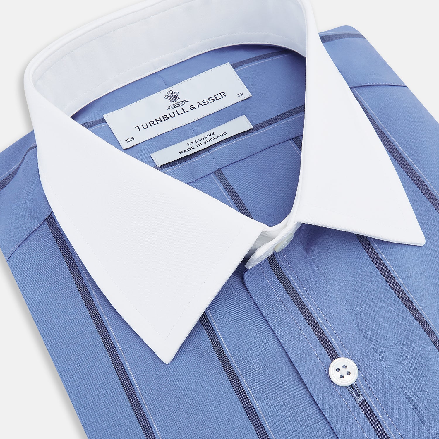 View 2 of product The Turnbull & Asser Colony Blue Track Stripe Shirt features vertical dark blue stripes, a Mayfair fit, and contrast white T&A collar and cuffs, reflecting British craftsmanship against a plain light background.