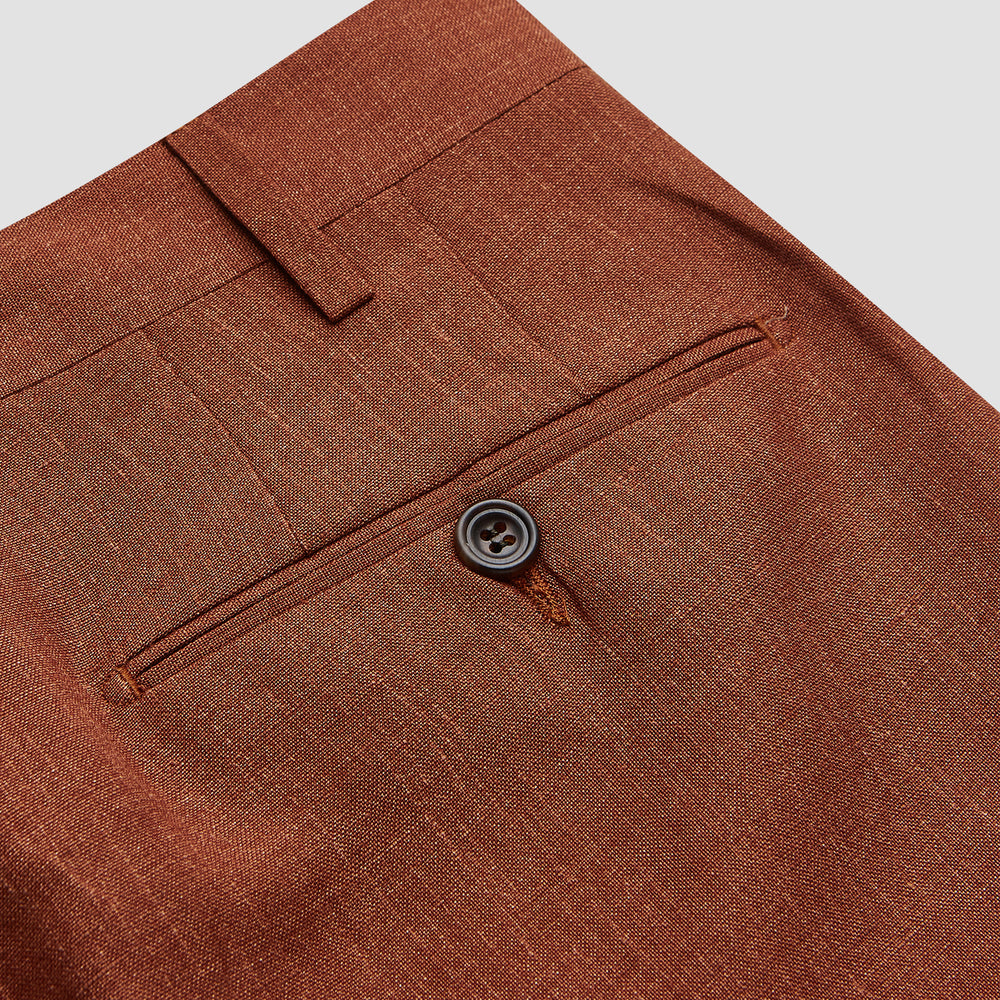 Turnbull & Asser’s Rust Linen-Wool-Silk Gerry Trousers, in a classic fit with straight legs, pleats, belt loops, and front button-zip closure, are neatly displayed flat on a white background.