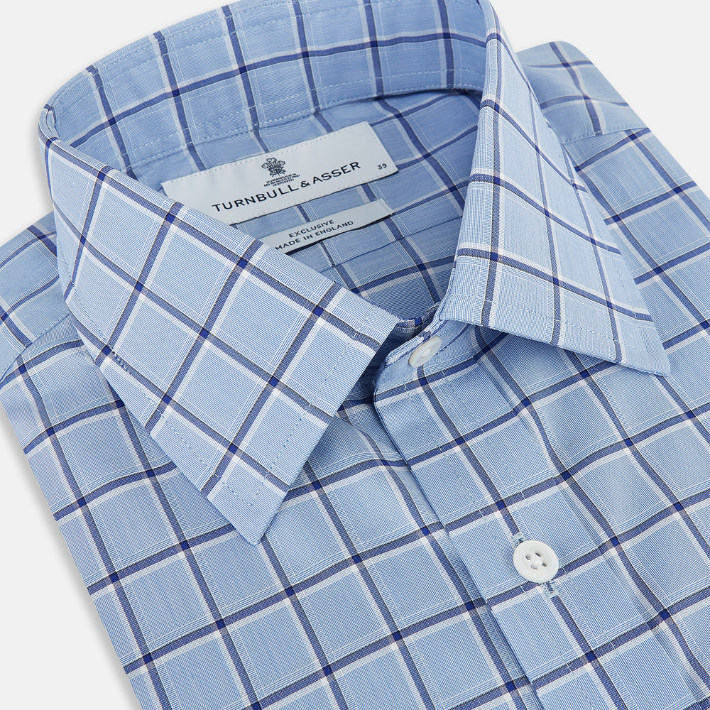 The Turnbull & Asser Blue and Navy Windowpane Mayfair Shirt features long sleeves, a T&A collar, buttoned cuffs, and Italian cotton in a blue and navy windowpane pattern, shown on a plain white background.