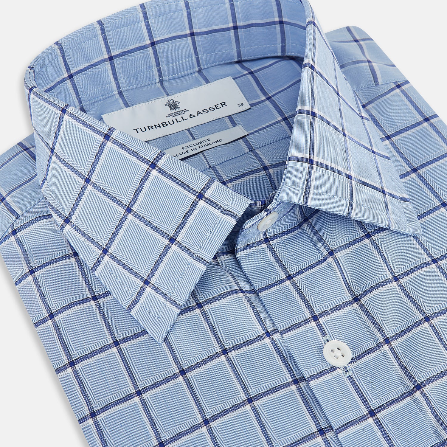 View 2 of product The Turnbull & Asser Blue and Navy Windowpane Mayfair Shirt features long sleeves, a T&A collar, buttoned cuffs, and Italian cotton in a blue and navy windowpane pattern, shown on a plain white background.