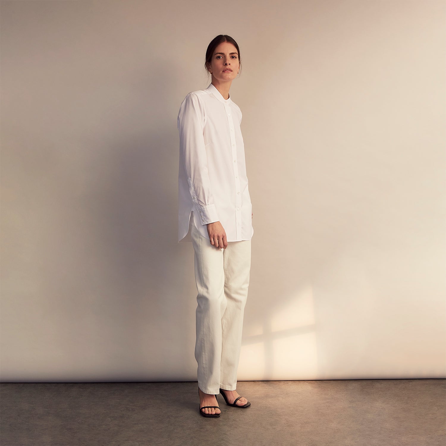 View 3 of product The White Cotton Lauren Shirt by Turnbull & Asser, featuring a stand collar, button-down front, and elongated body, is laid flat on a plain white background.