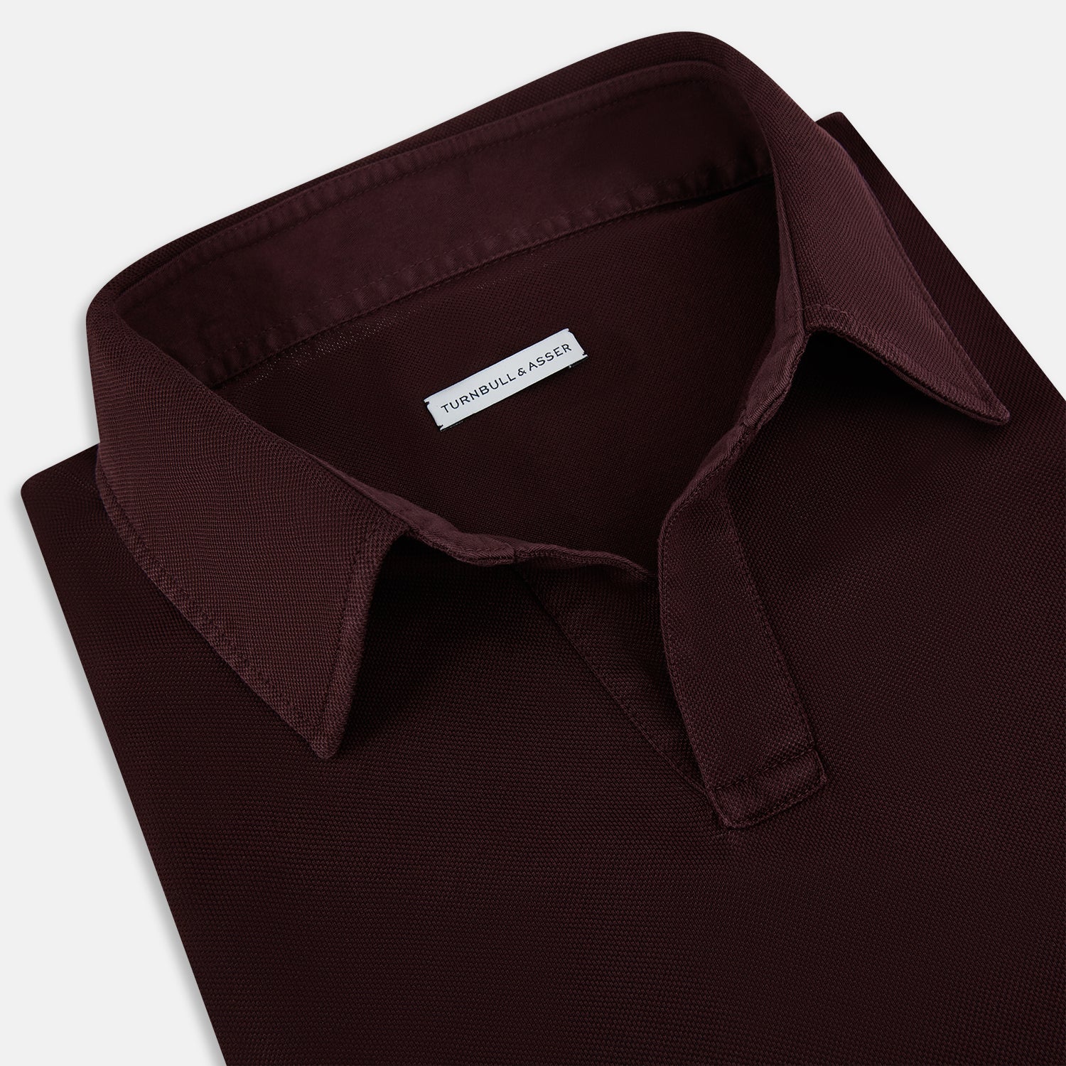 View 2 of product The Turnbull & Asser Burgundy Rugby Polo Shirt is a long-sleeve, pure cotton collared top with no visible buttons, shown laid flat on a white background.