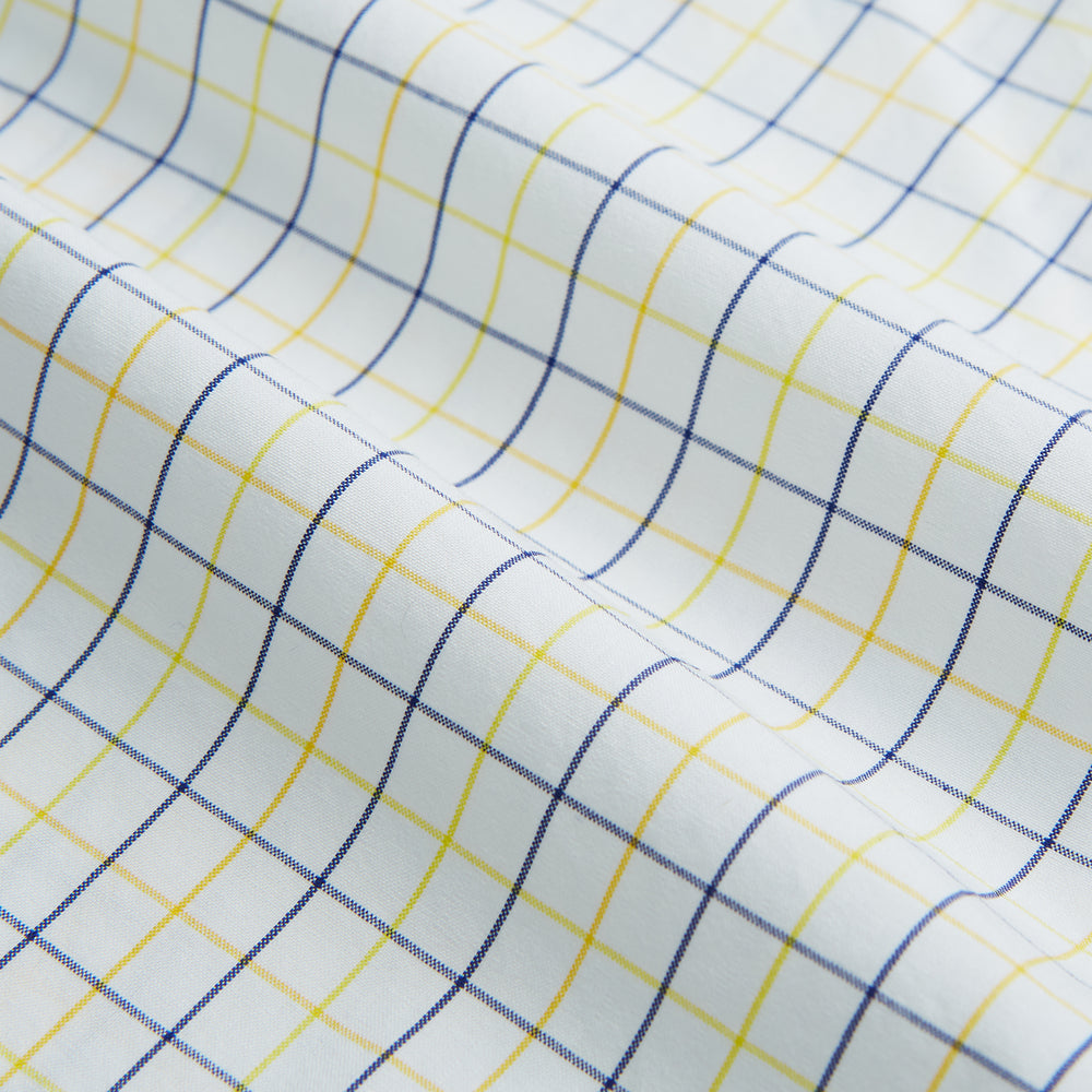 The Turnbull & Asser Yellow Overlay Grid Check Mayfair Shirt is a long-sleeve, button-down shirt made from soft organic cotton, featuring a yellow grid check pattern and shown laid flat on a white background.