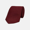 View 1 of product The Turnbull & Asser 7 fold Grenadine Silk Plain Tie is shown rolled on a white background, highlighting its textured maroon design as a versatile addition to any wardrobe.