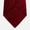 View 4 of product The Turnbull & Asser Plain Herringbone Burgundy Tie features a subtle pattern and rich color, making it an essential accessory for smart attire. Neatly rolled, it’s elegantly displayed on a plain white background.