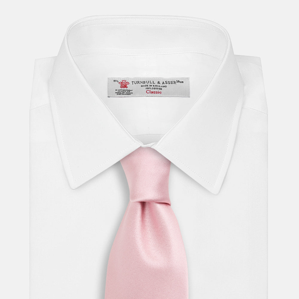 The Turnbull & Asser PINK PLAIN SATIN SILK TIE is neatly rolled and showcased against a plain white background.