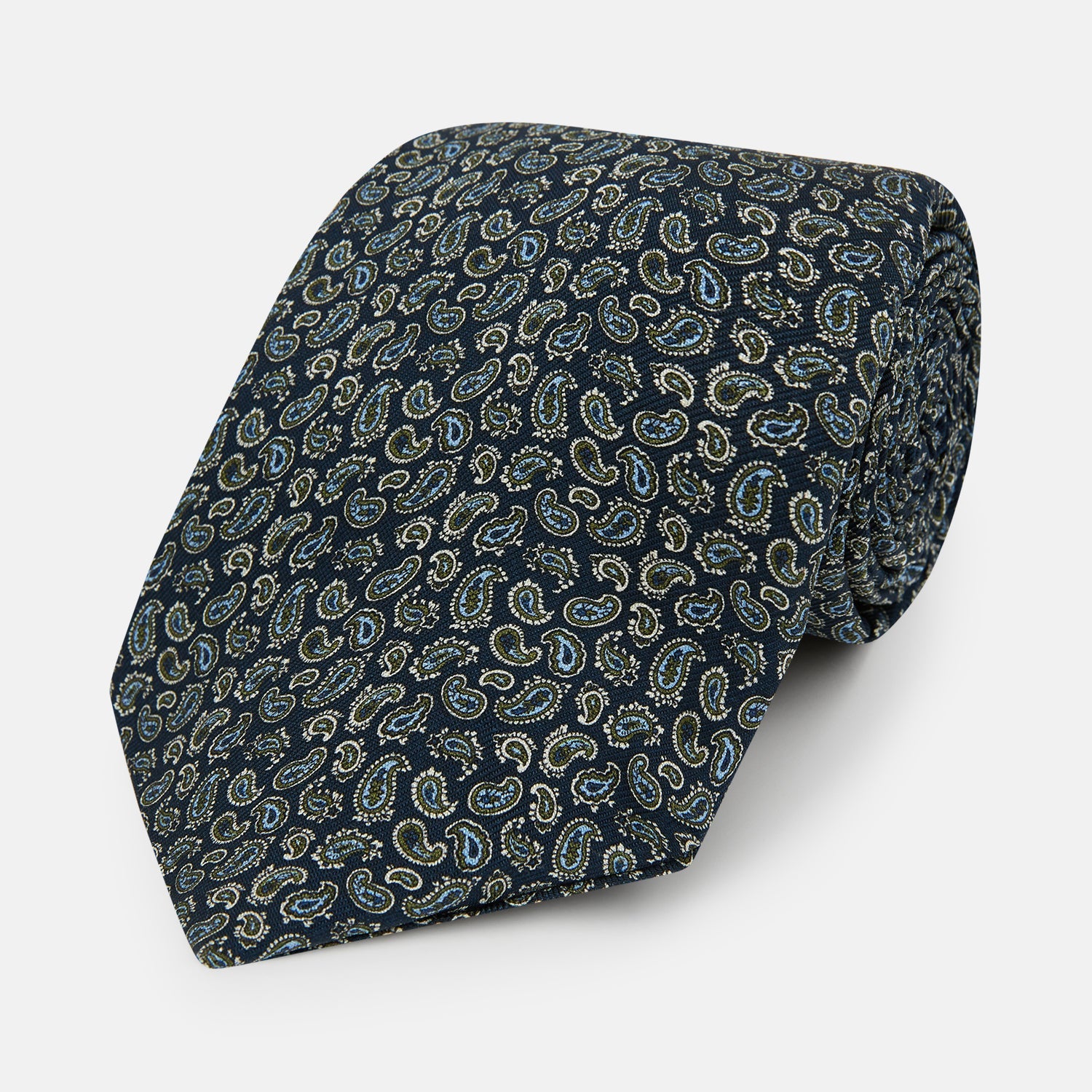 View 1 of product The Turnbull & Asser Navy Paisley Foulard Silk Tie features a refined paisley pattern in blue, white, and beige tones, elegantly rolled and presented against a white background.