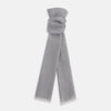 View 1 of product The Grey Cashmere Scarf by Turnbull & Asser, displayed folded with a loose knot on a white background, showcases semi-sheer luxury in light gray—an elegant accessory.