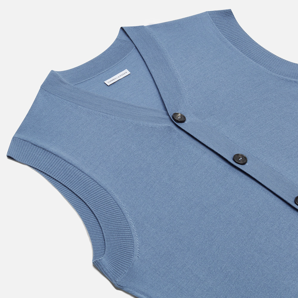 Turnbull & Asser’s Pale Blue Merino V-neck Sleeveless Cardigan features a button-up front, two pockets, and ribbed hem—a classic gentleman’s piece shown on a plain white background.