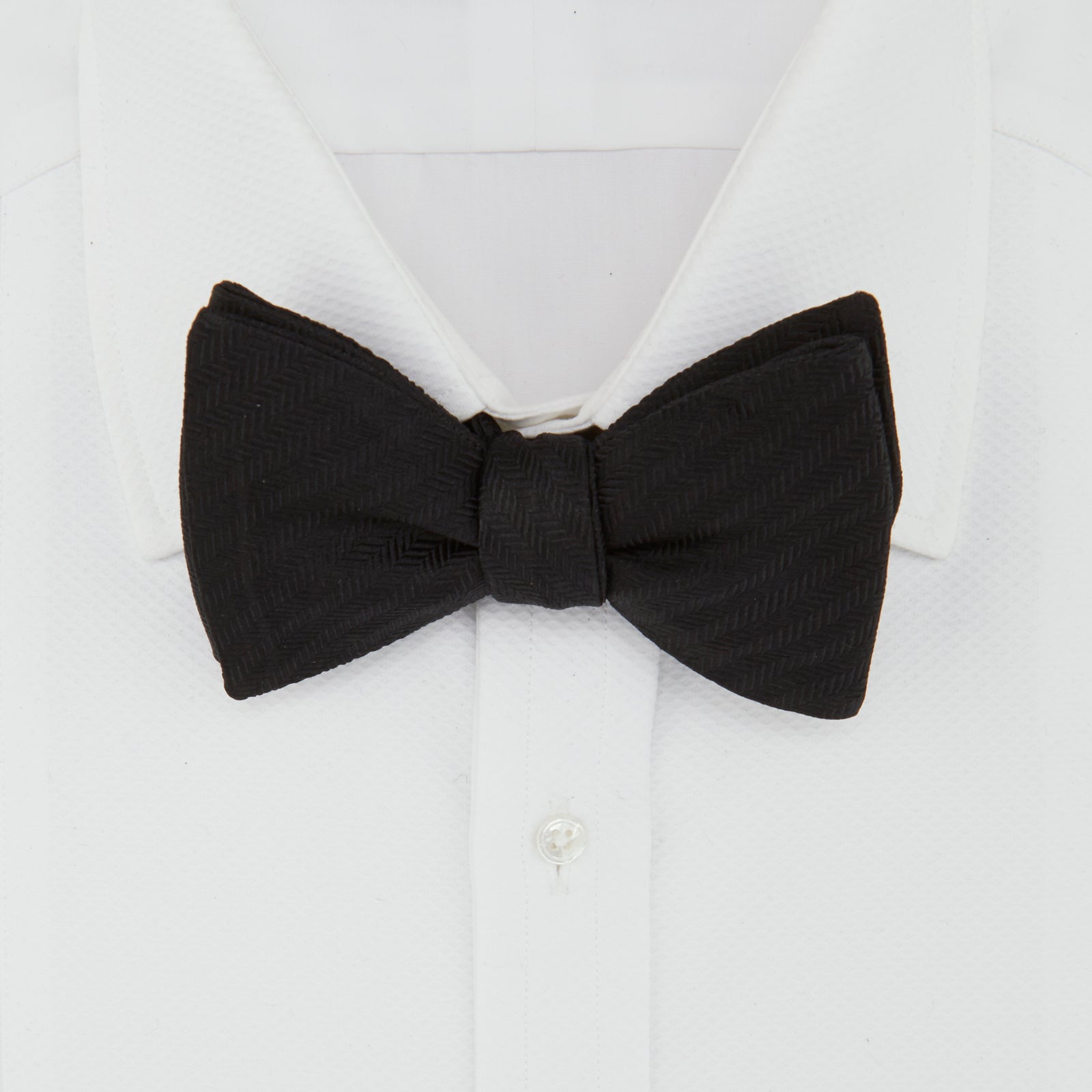 View 2 of product The Turnbull & Asser Black Herringbone Silk Bow Tie, ideal for formal occasions, features a subtle herringbone pattern and is shown against a plain white background.