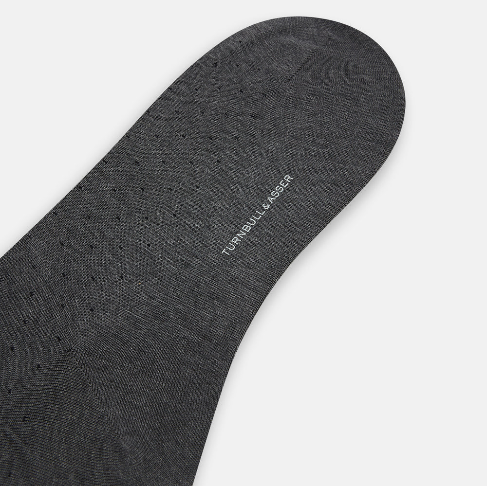 The image shows a single Turnbull & Asser Dark Steel/Navy Polka Dot Mid-Length Sock standing upright on a plain white background, featuring a ribbed cuff and a smooth, seamless finish.