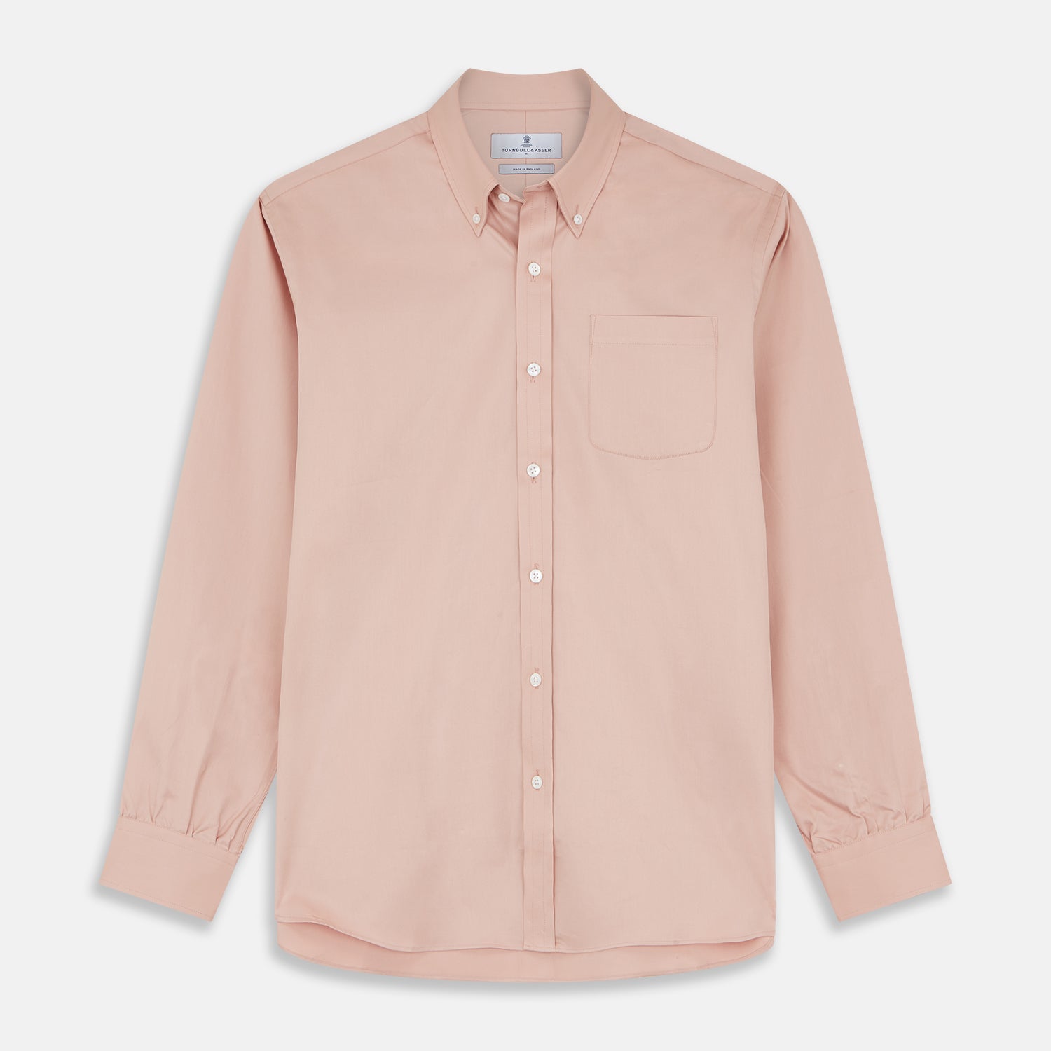 View 2 of product A man faces forward in a relaxed pose against a beige background, wearing the Turnbull & Asser Pink Piece Dyed Weekend Fit Suffolk Shirt with a button-down collar, dark cuffed jeans, and black shoes.
