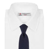 View 2 of product The Turnbull & Asser White and Navy Spot Printed Silk Tie, shown rolled with its pointed end forward on a white background, is an elegant accessory that pairs perfectly with a crisp shirt for smart occasions.
