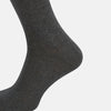 View 4 of product The Turnbull & Asser Steel/midnight Polka Dot Long Sock is shown in dark gray over the calf, displayed from the side on a white background with downward toe and ribbed top for a snug fit.