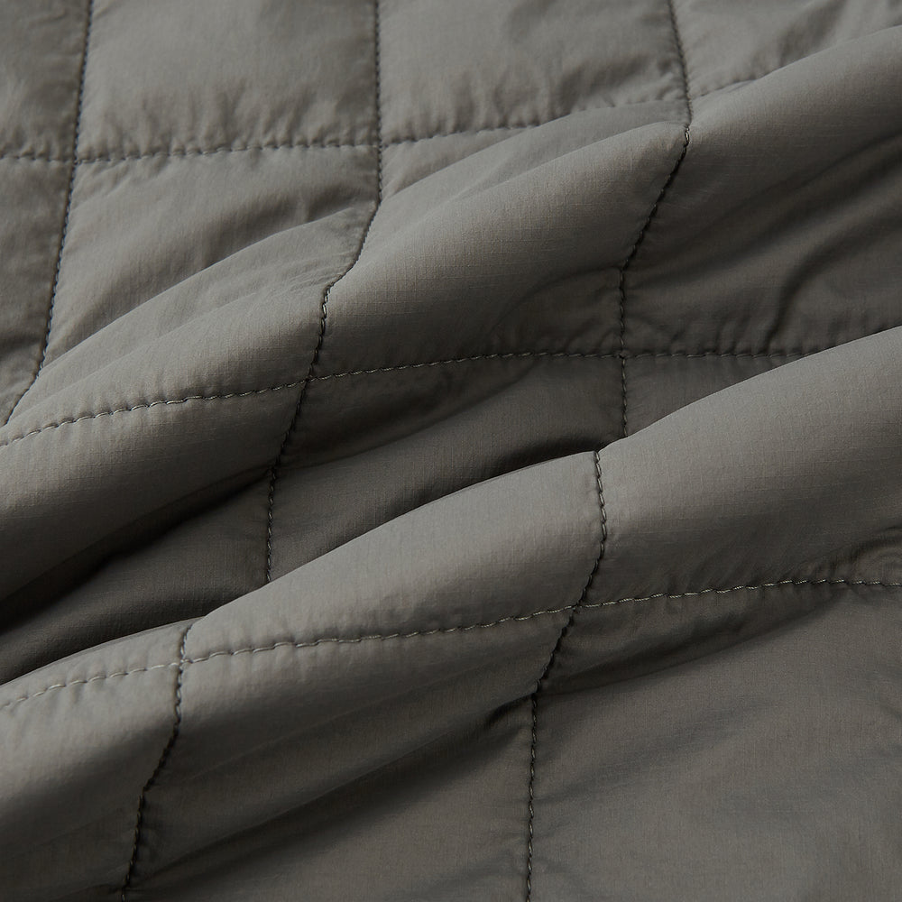 The Shadow Grey Quilted Gilet by Turnbull & Asser is a sleeveless, lightweight layer featuring a front zipper, two zippered side pockets, one chest pocket, and a rounded hem—shown on a plain white background.