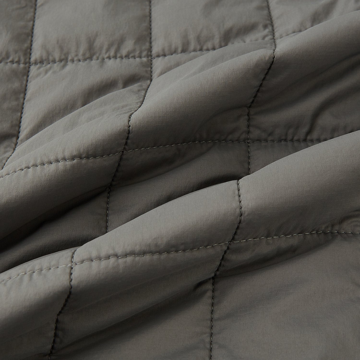 View 4 of product The Shadow Grey Quilted Gilet by Turnbull & Asser is a sleeveless, lightweight layer featuring a front zipper, two zippered side pockets, one chest pocket, and a rounded hem—shown on a plain white background.