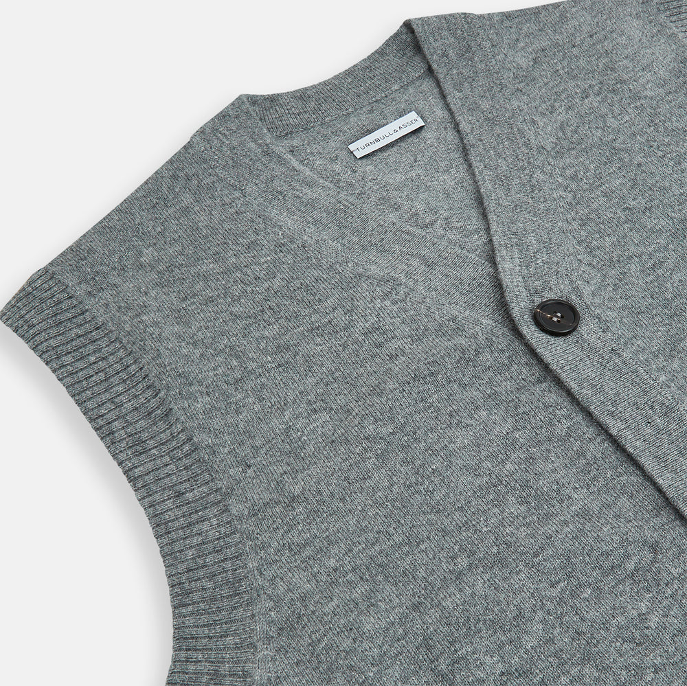 The Turnbull & Asser Ash Grey V-neck Sleeveless Cardigan features a button-up front, two front pockets, and ribbed edges, shown against a plain white background.