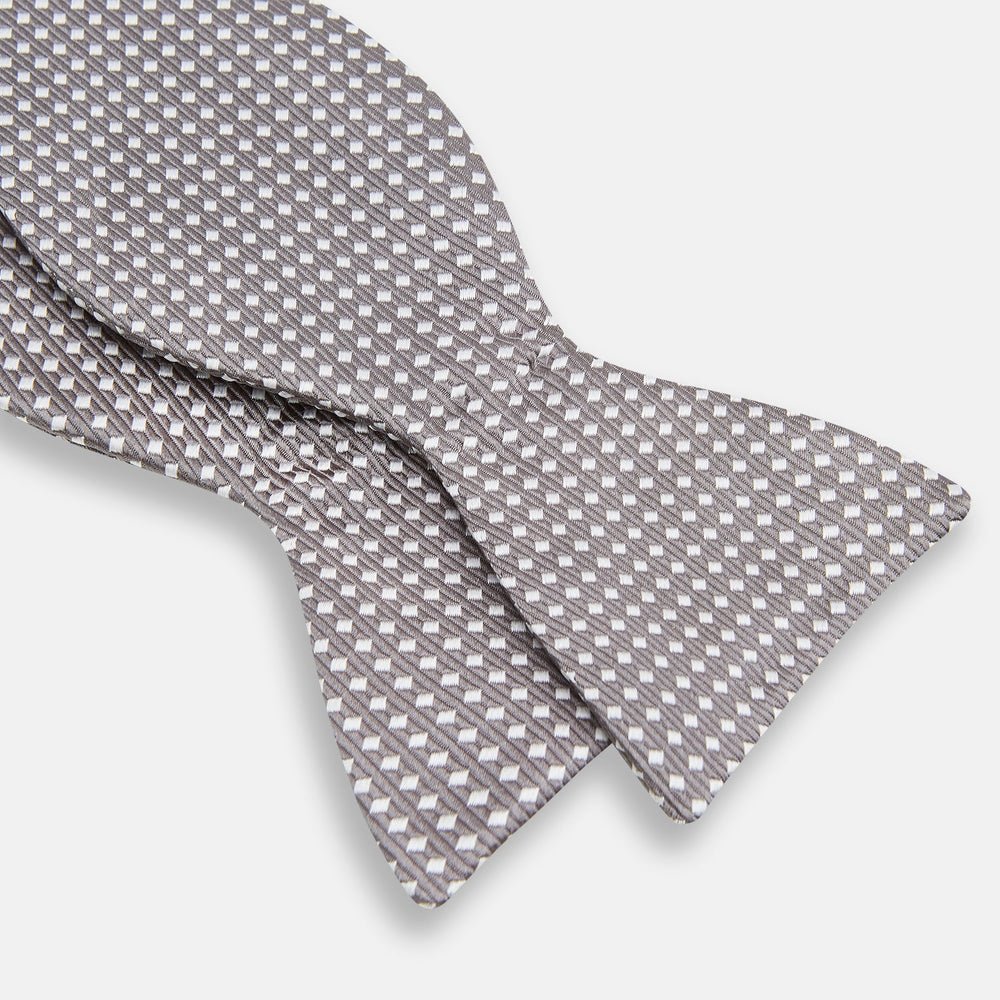 The Turnbull & Asser Grey and White Diamond Silk Bow Tie showcases a subtle diamond pattern, ideal for formalwear, and is elegantly displayed against a plain white background.