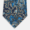 View 4 of product The Turnbull & Asser Blue and Navy Twisted Paisley Silk Tie displays intricate blue, white, and black details, rolled up against a plain white background.