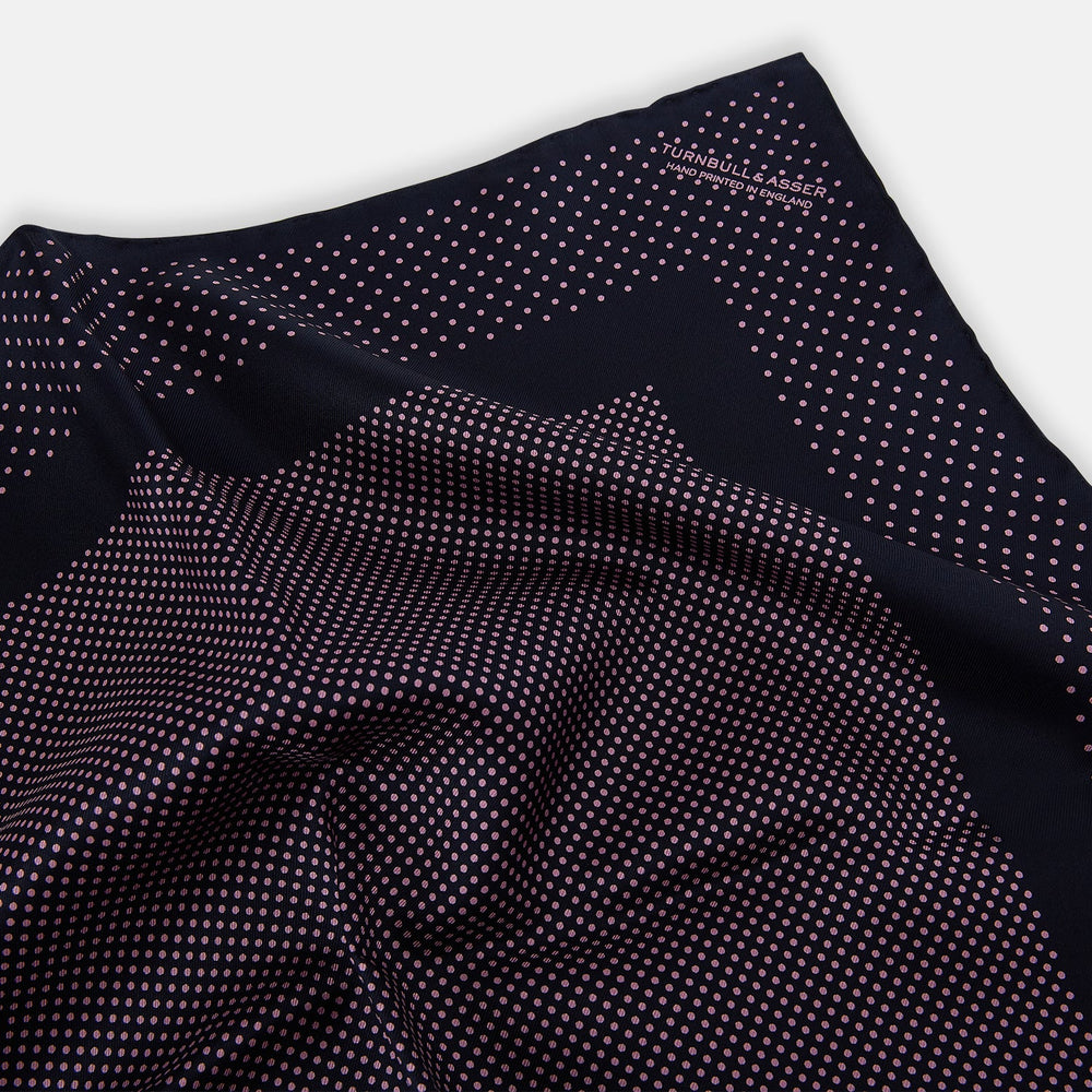 The Turnbull & Asser Navy and Pink Dot Silk Pocket Square features small pink dots and a solid border, with one corner folded to display both sides—an elegant accessory that reflects fine handmade craftsmanship.